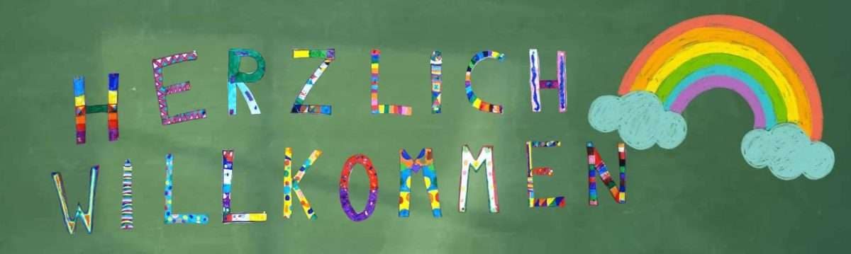 Bunte Buchstaben auf einer Tafel, die 'Herzlich Willkommen' sagen, mit einem Regenbogen und einer Wolke.