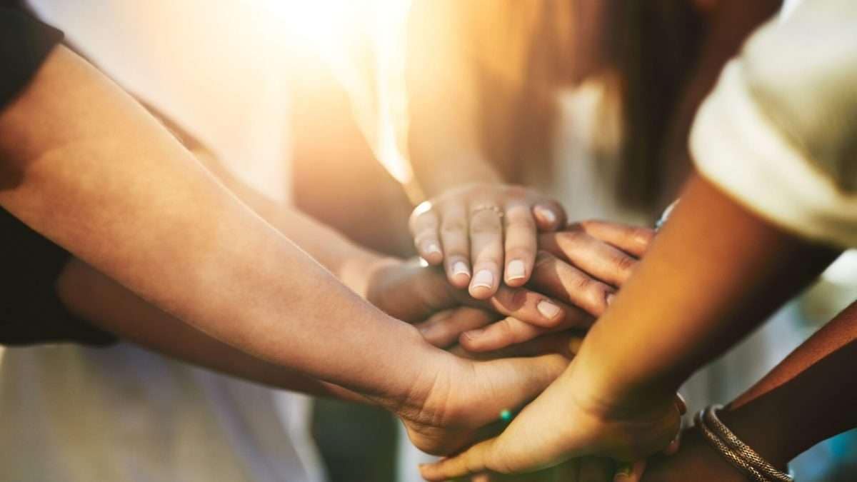 Mehrere Hände, die übereinander gelegt sind, symbolisieren Teamarbeit und Zusammenarbeit.