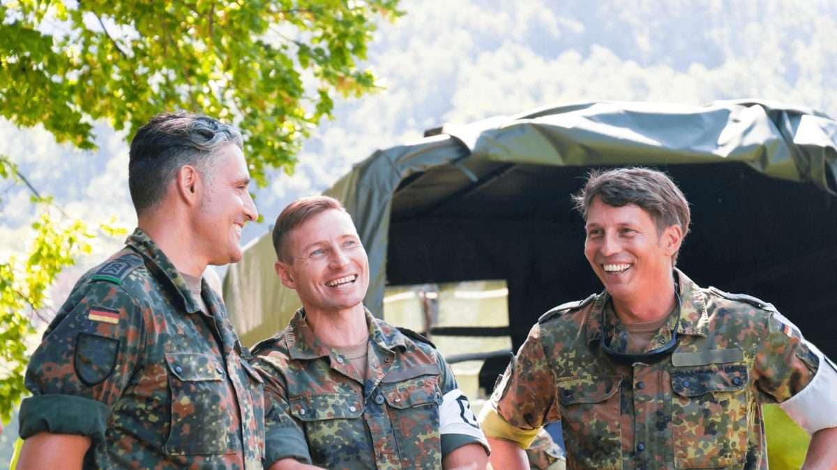 Drei Bundeswehrsoldaten in Uniform, die miteinander sprechen und lachen.