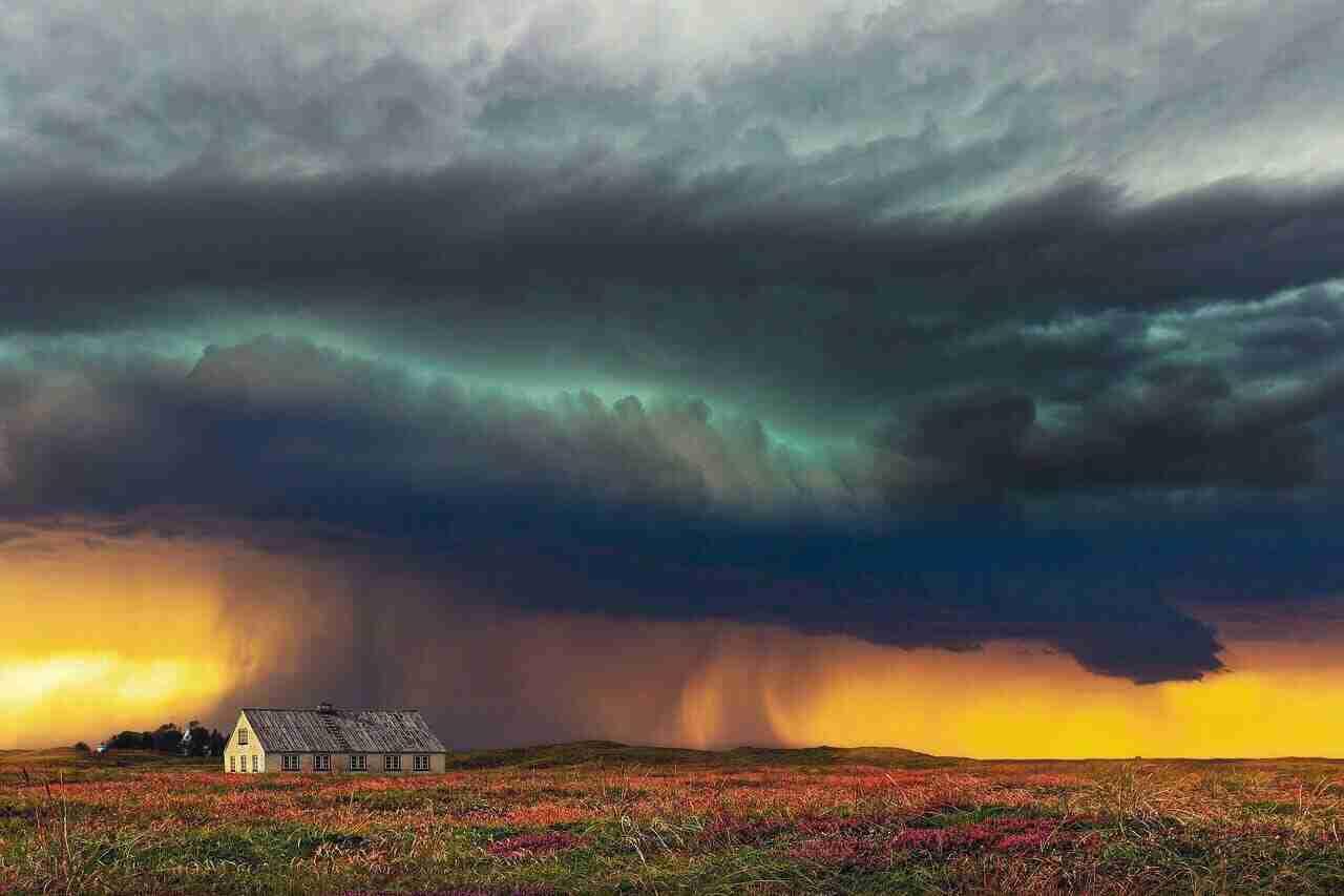 Ein einfaches Haus steht unter einem dramatischen, stürmischen Himmel mit dunklen Wolken und Regen.