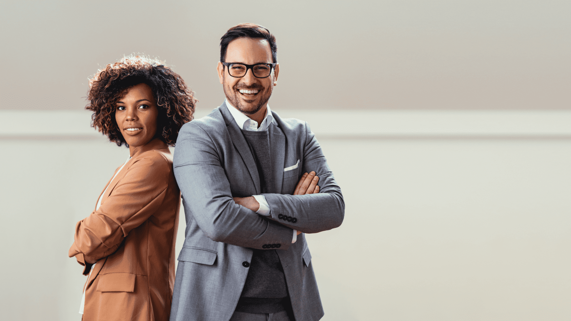 Ein Mann und eine Frau stehen Rücken an Rücken, beide in formeller Kleidung, mit neutralem Gesichtsausdruck.