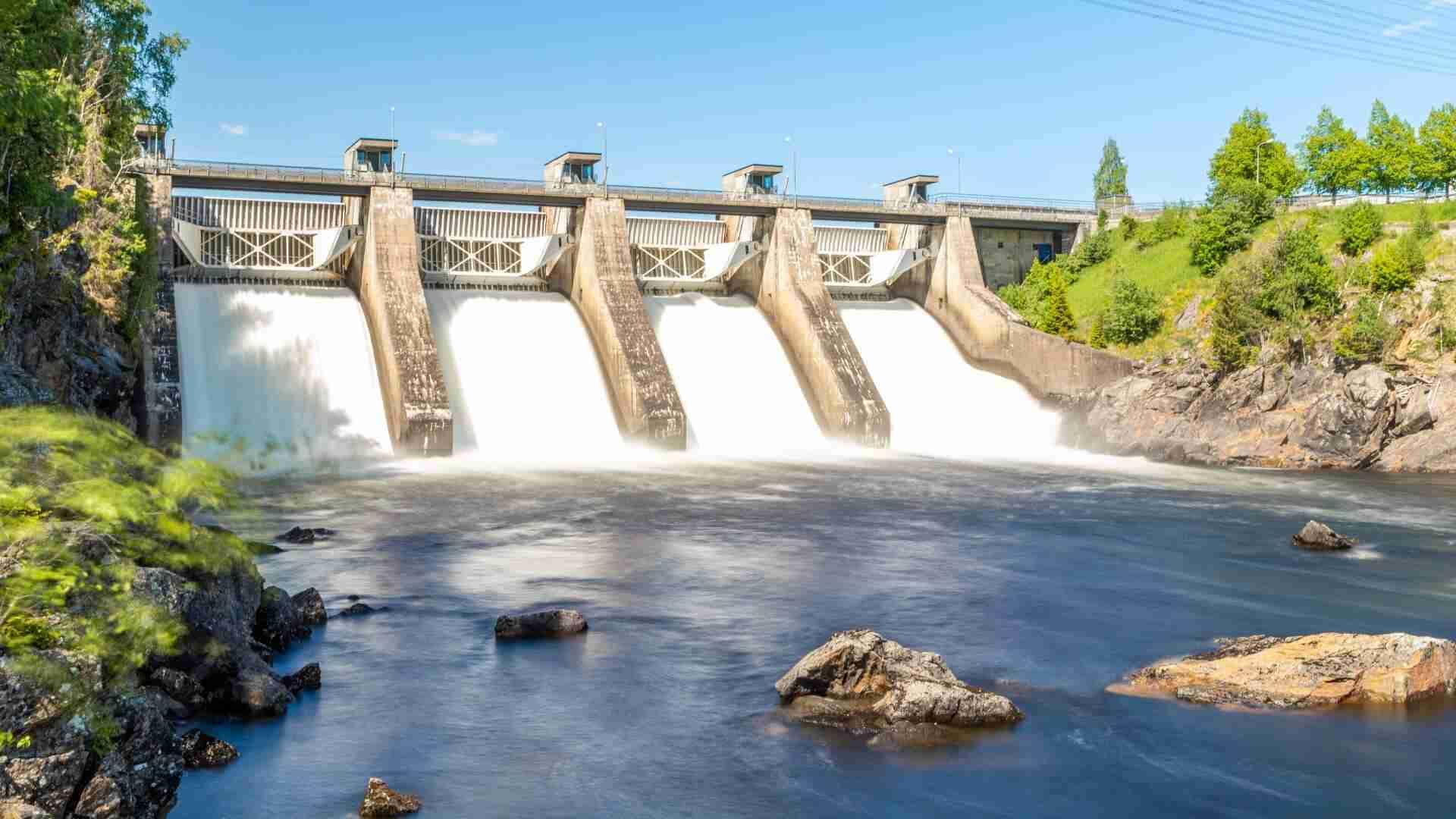 Wasserkraftwerk mit mehreren Turbinen, die Wasser in einen Fluss leiten.