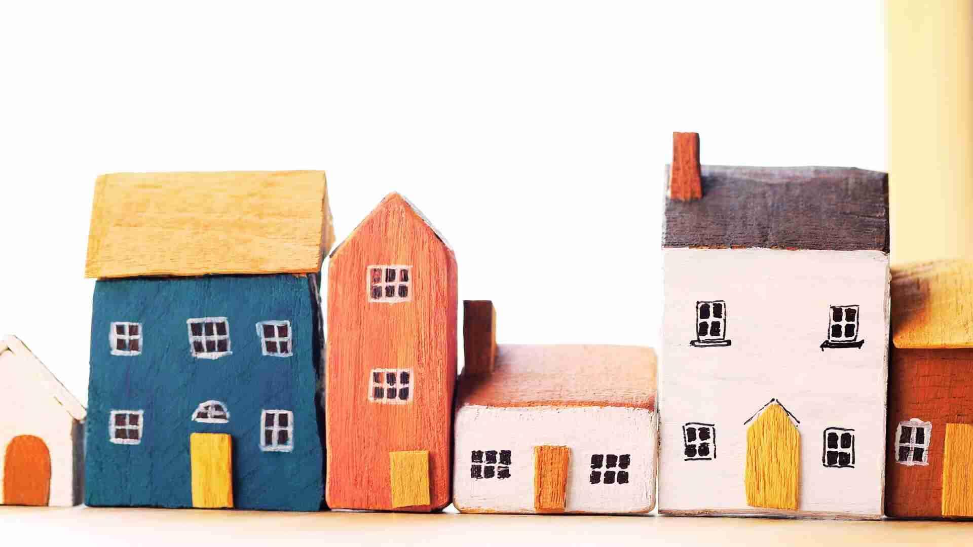 Reihe von farbigen Holzhausmodellen in verschiedenen Formen und Farben auf einem hellen Hintergrund.