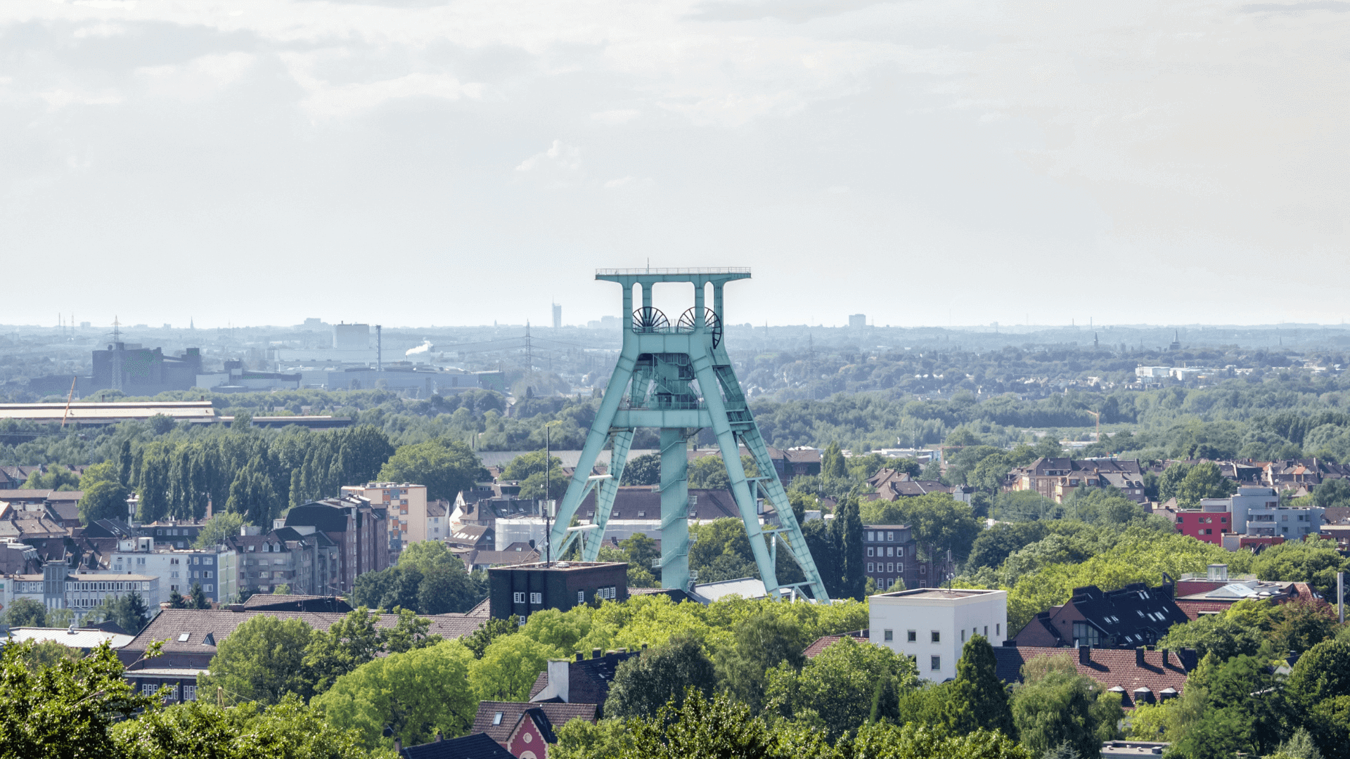 Förderturm in Bochum, umgeben von städtischer Landschaft und Bäumen.