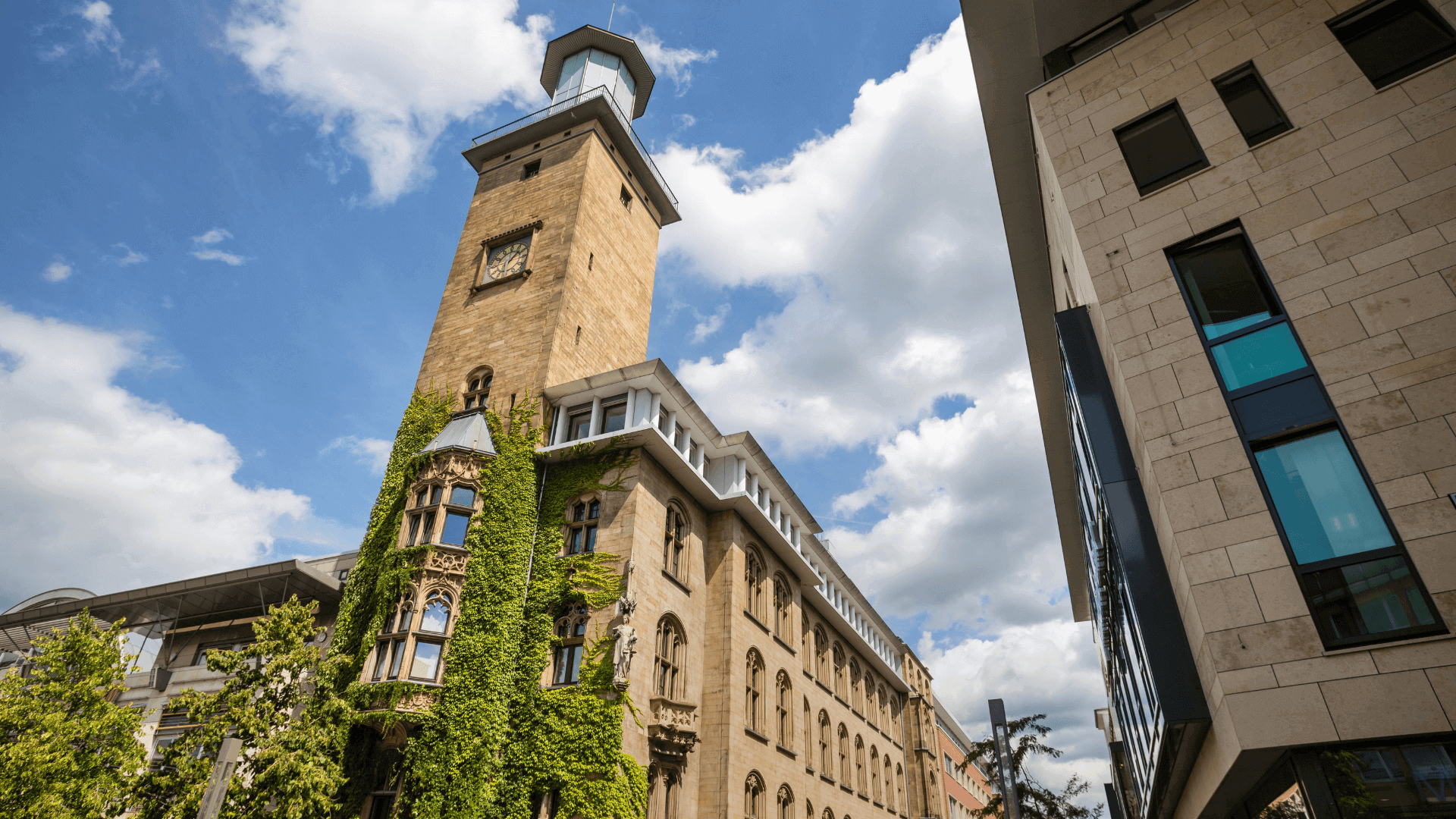 Historisches Gebäude mit einem hohen Turm und Pflanzen, die die Fassade bedecken.