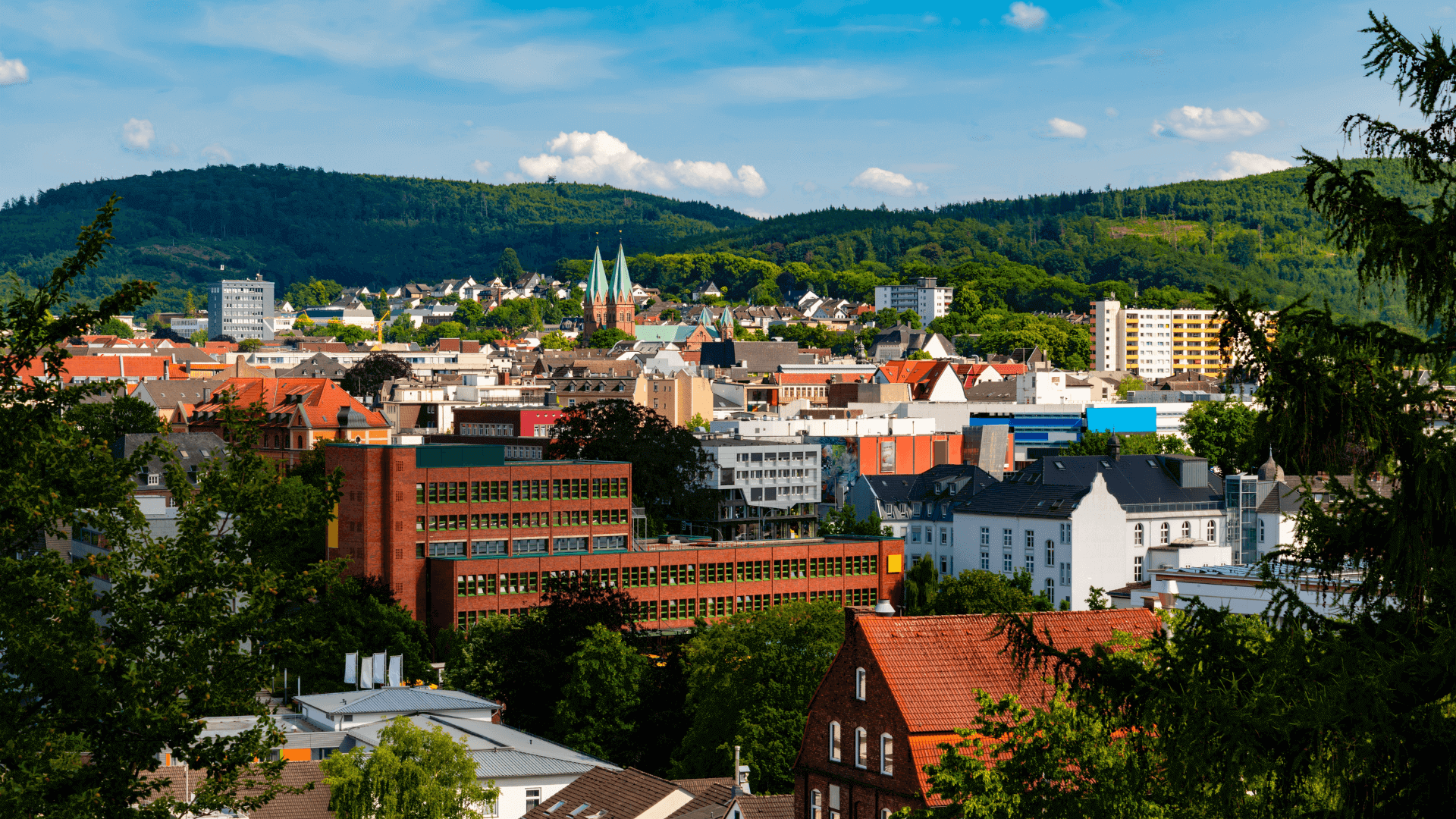 Blick auf die Stadt Iserlohn mit Gebäuden und grünen Hügeln im Hintergrund.