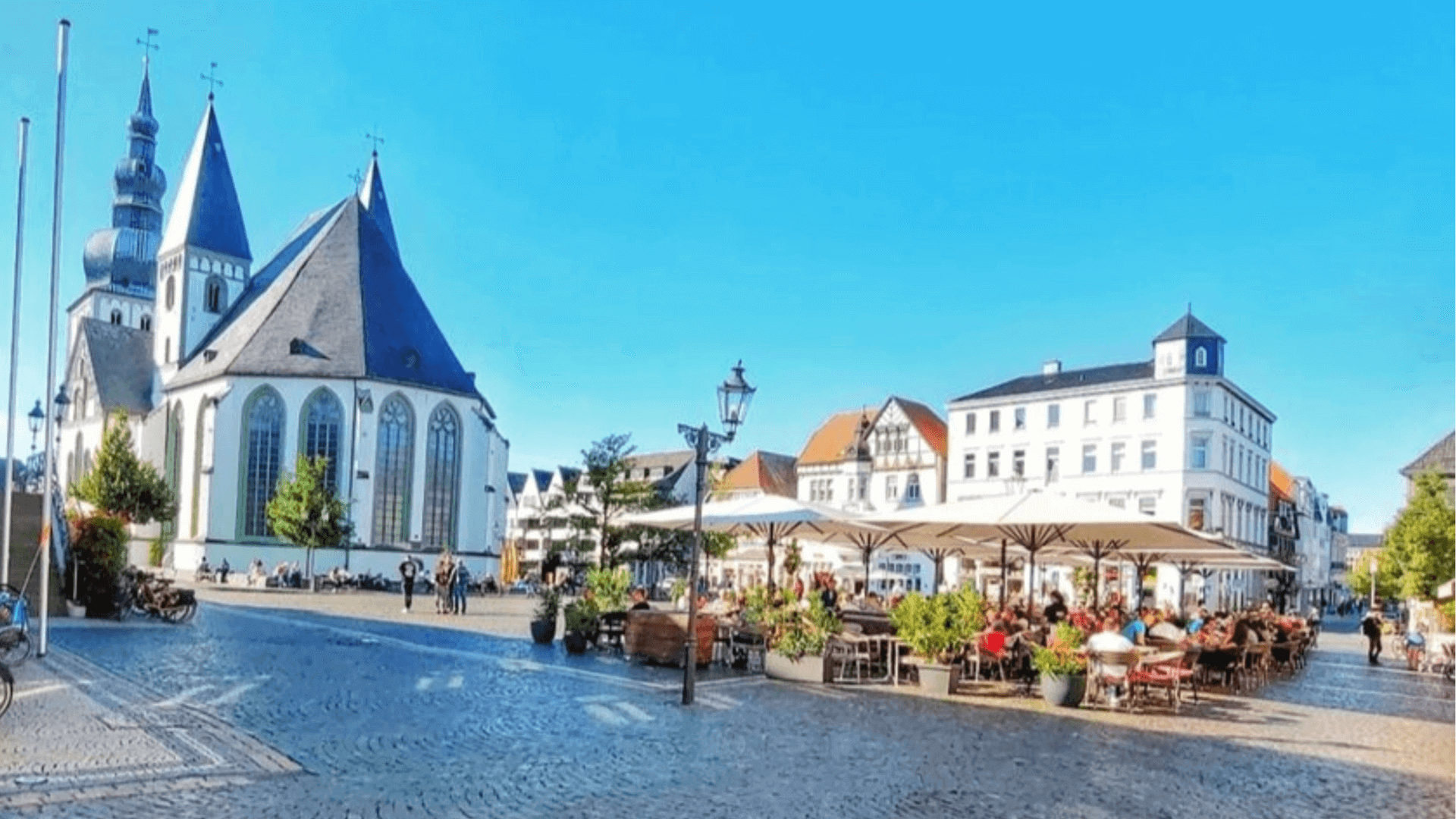 Stadtansicht von Lippstadt mit einer Kirche und mehreren Cafés im Freien.