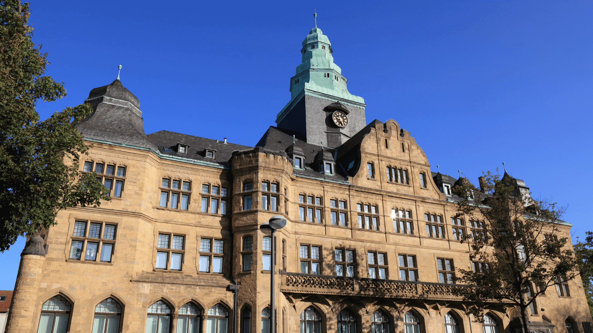 Historisches Gebäude mit einem hohen Turm und einer grünen Kuppel in Recklinghausen unter blauem Himmel.