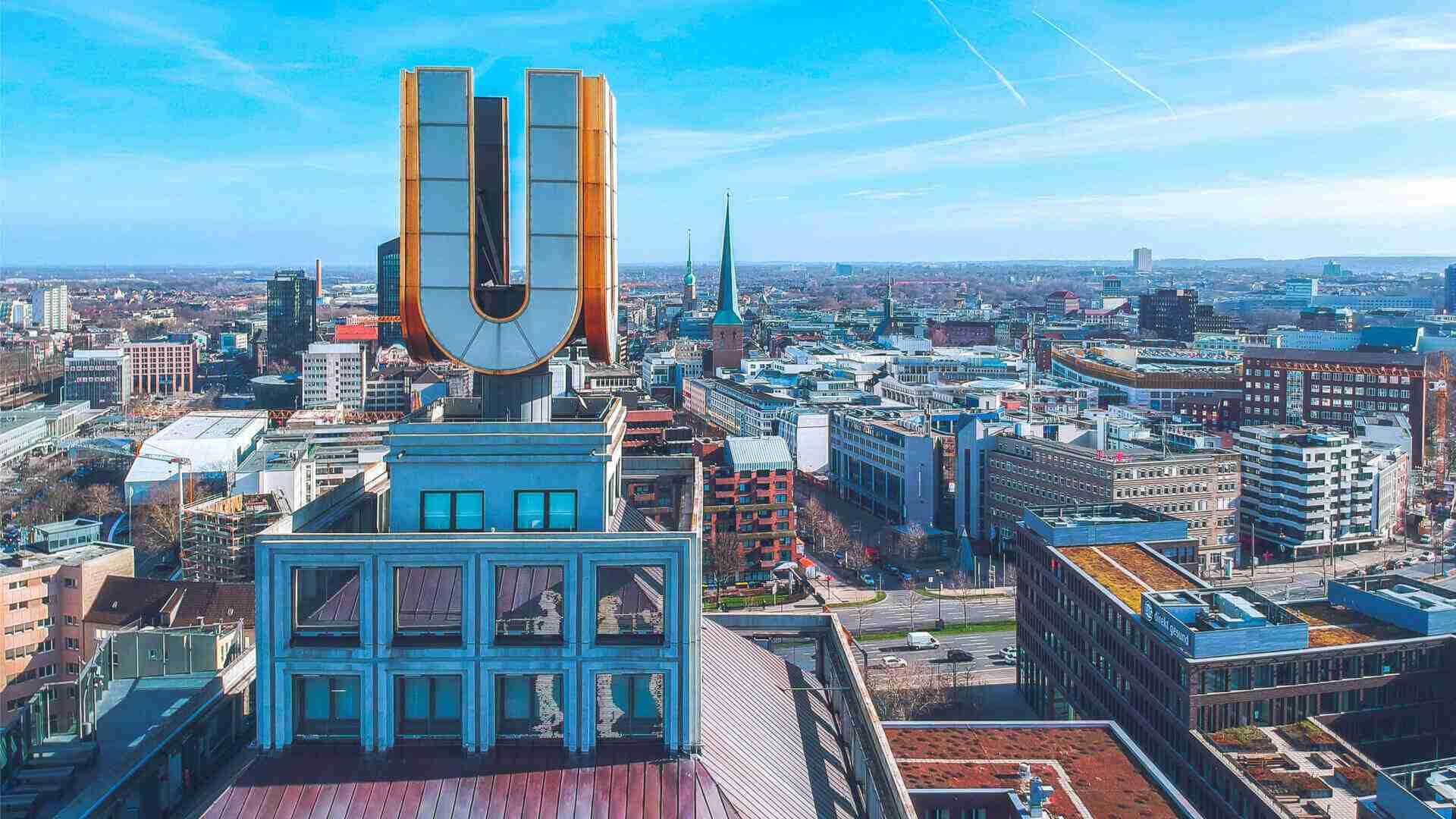 Luftaufnahme des U-Turms in Dortmund mit dem charakteristischen U-Symbol und der Stadtlandschaft im Hintergrund.