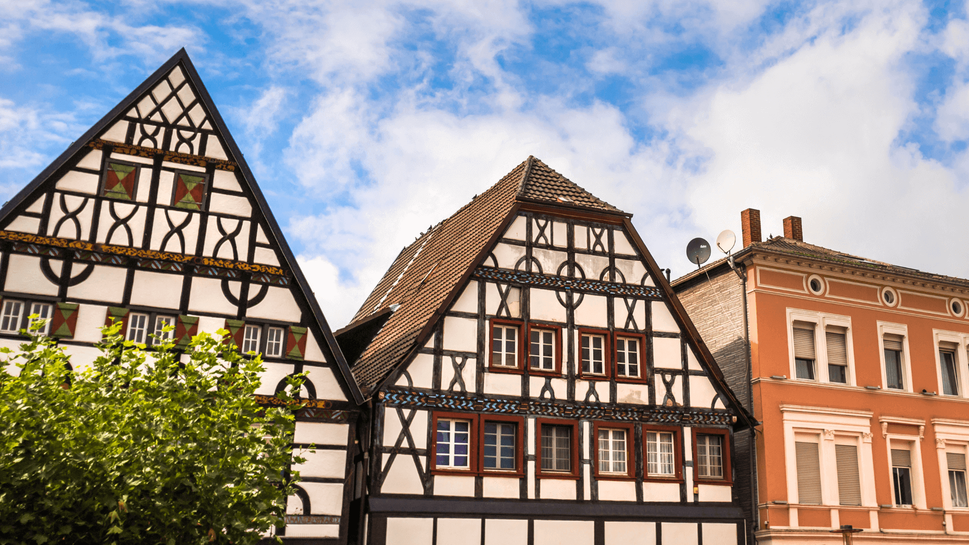 Zwei Fachwerkhäuser mit sichtbaren Holzrahmen und bunten Fenstern in Unna.