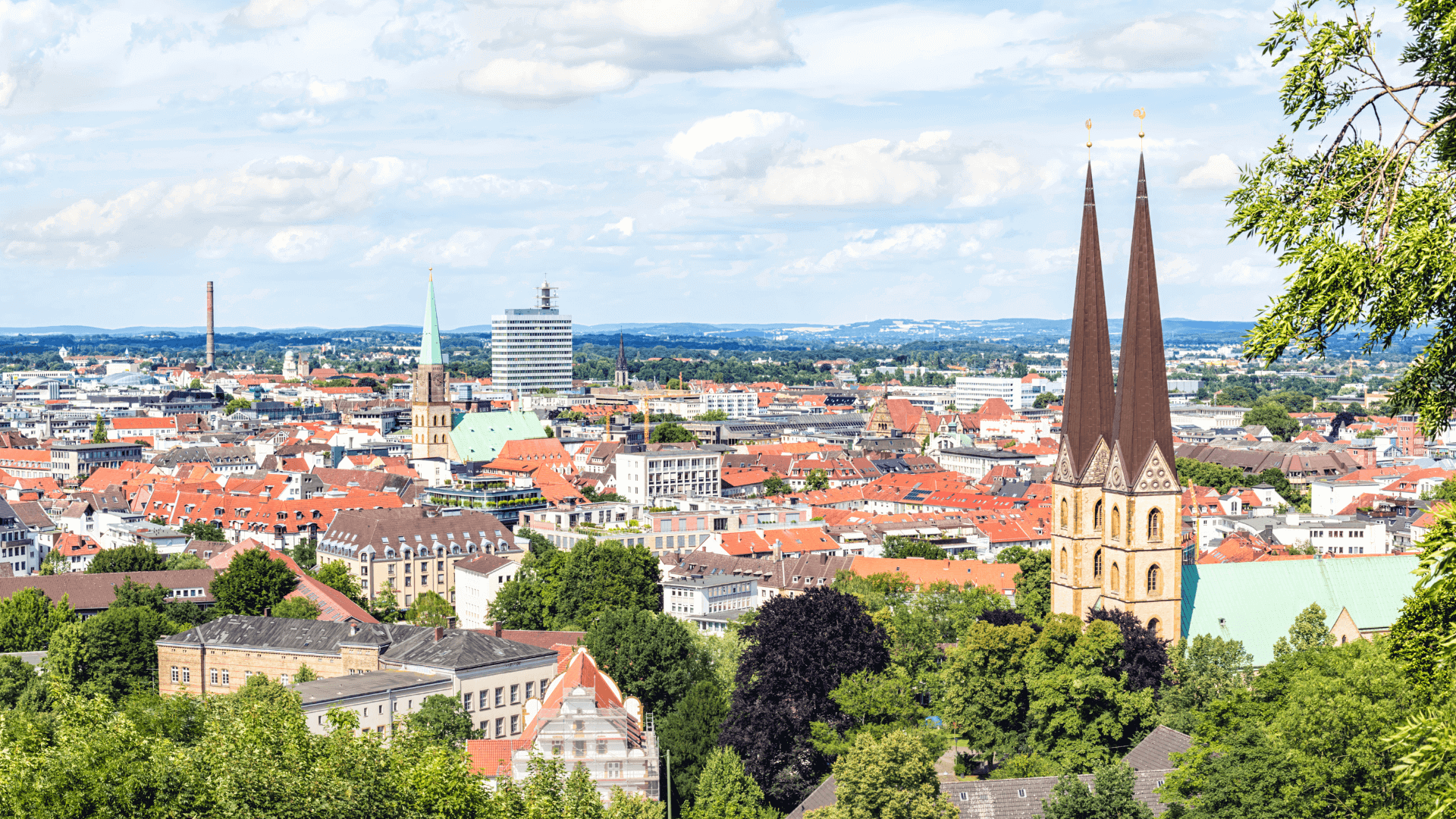 Panoramablick auf die Stadt Bielefeld mit markanten Kirchtürmen und modernen Gebäuden.