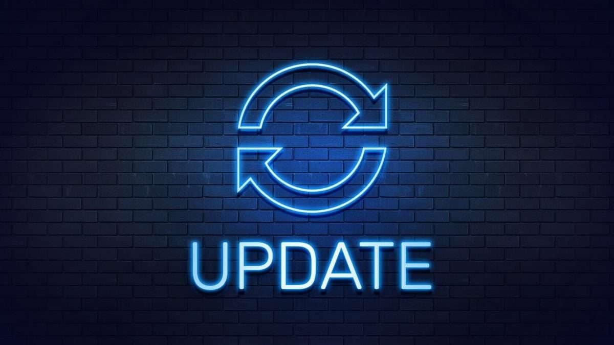 Neon-Schild mit dem Wort 'Update' und einem kreisförmigen Pfeilsymbol auf einer Ziegelwand.