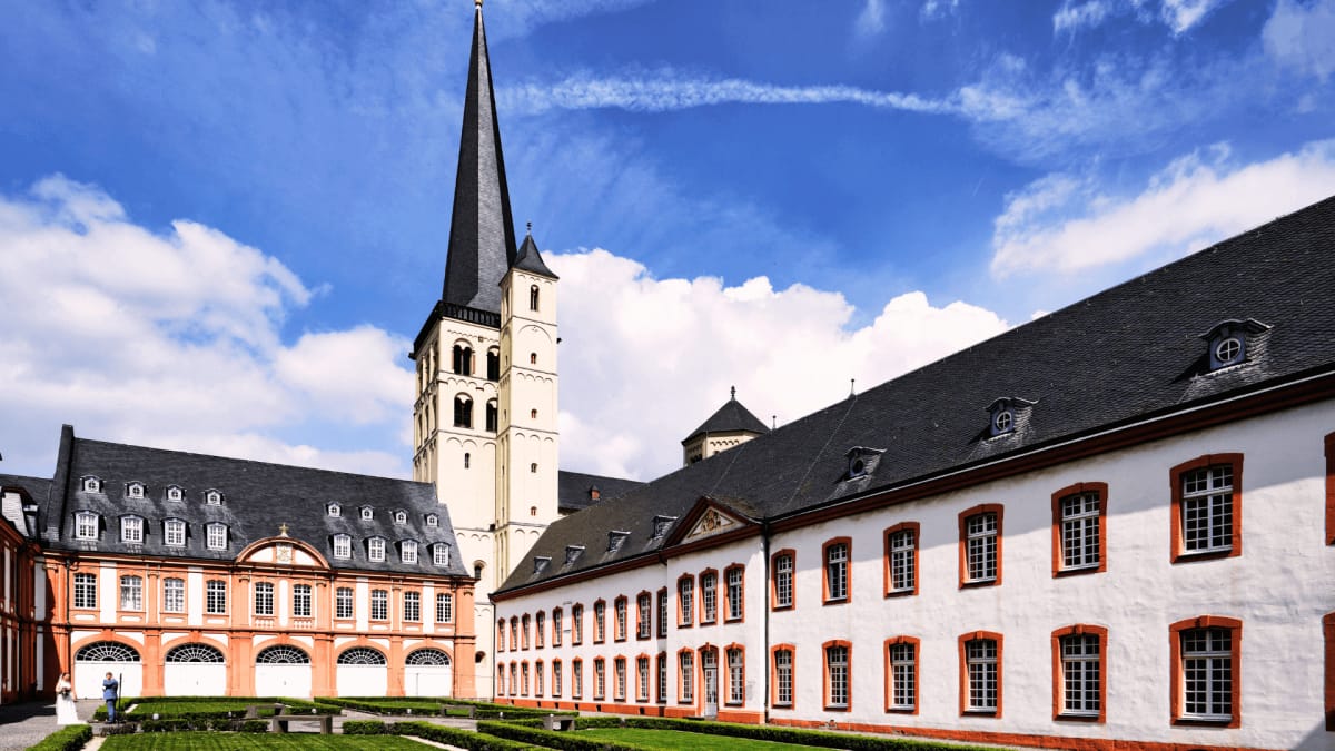 Blick auf die Pulheimer Kirche mit einem hohen Turm und angrenzenden historischen Gebäuden.