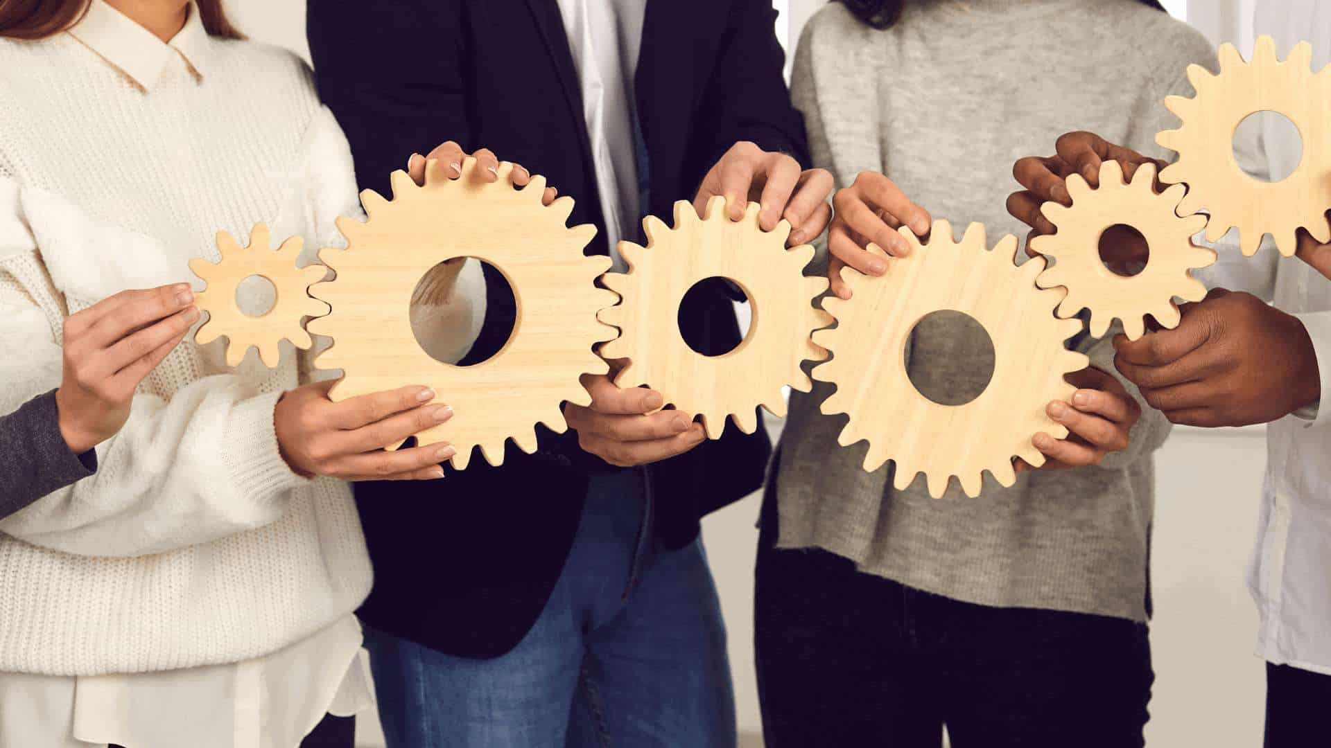 Mehrere Personen halten Holzgetriebe in einer Gruppeninteraktion, die miteinander verbunden sind.