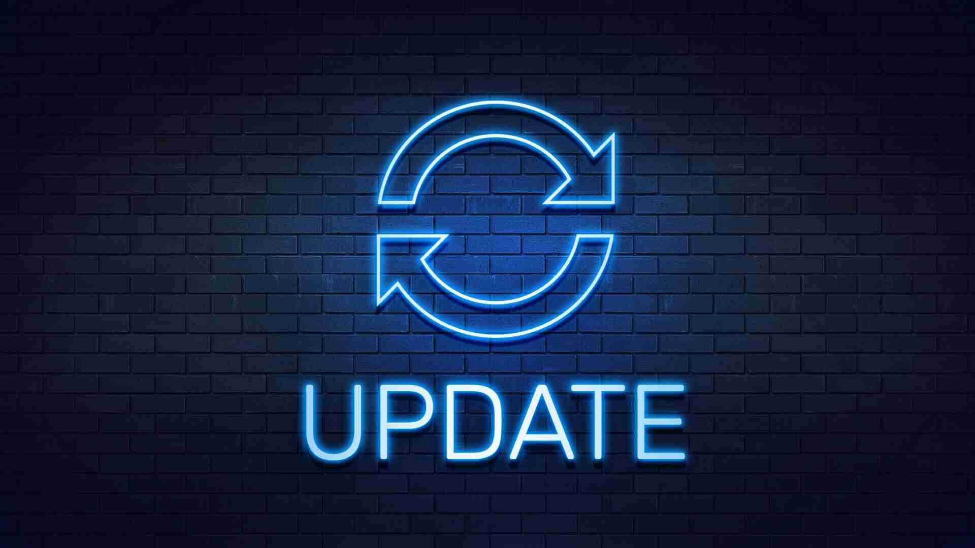 Neon-Symbol mit zwei Pfeilen in einem Kreis und dem Wort 'UPDATE' darunter auf einer Ziegelwand.