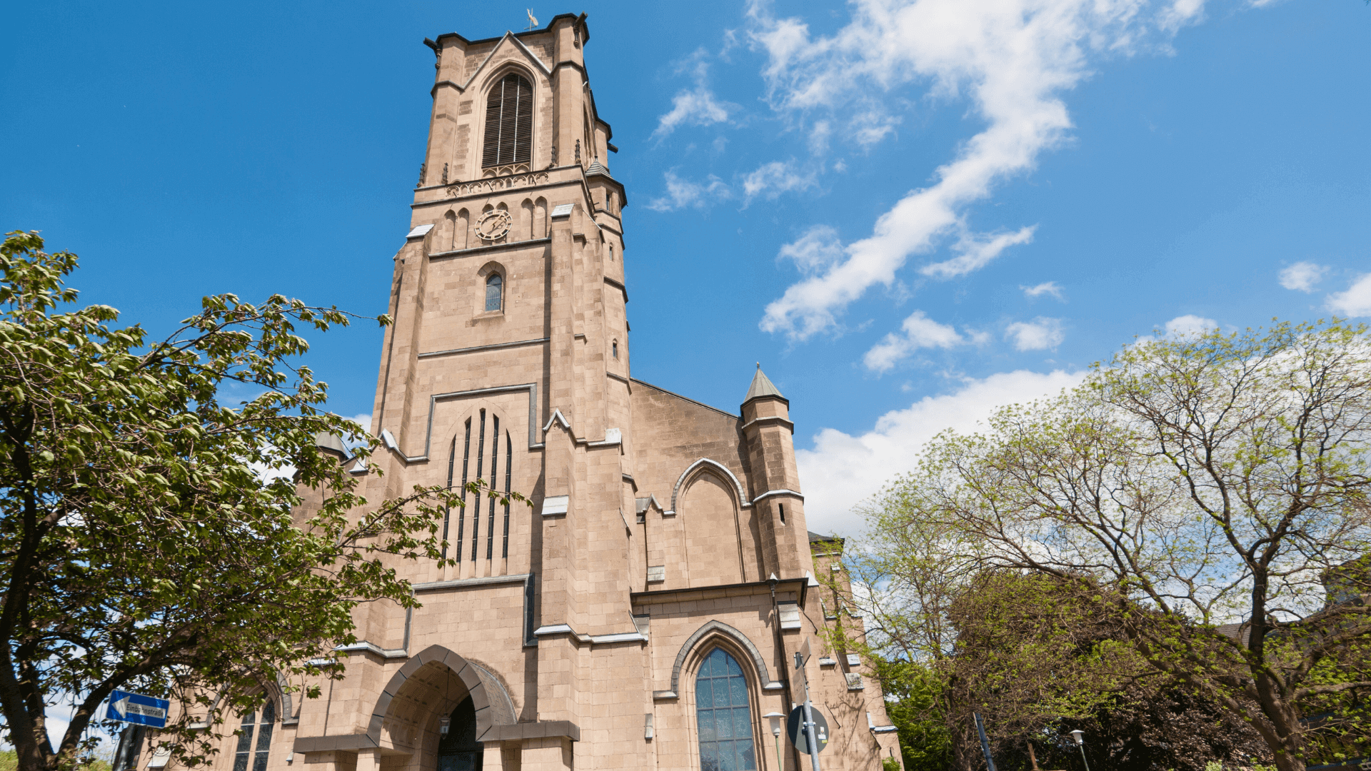 Hochgotische Kirche mit markantem Turm und detaillierter Fassade unter blauem Himmel.