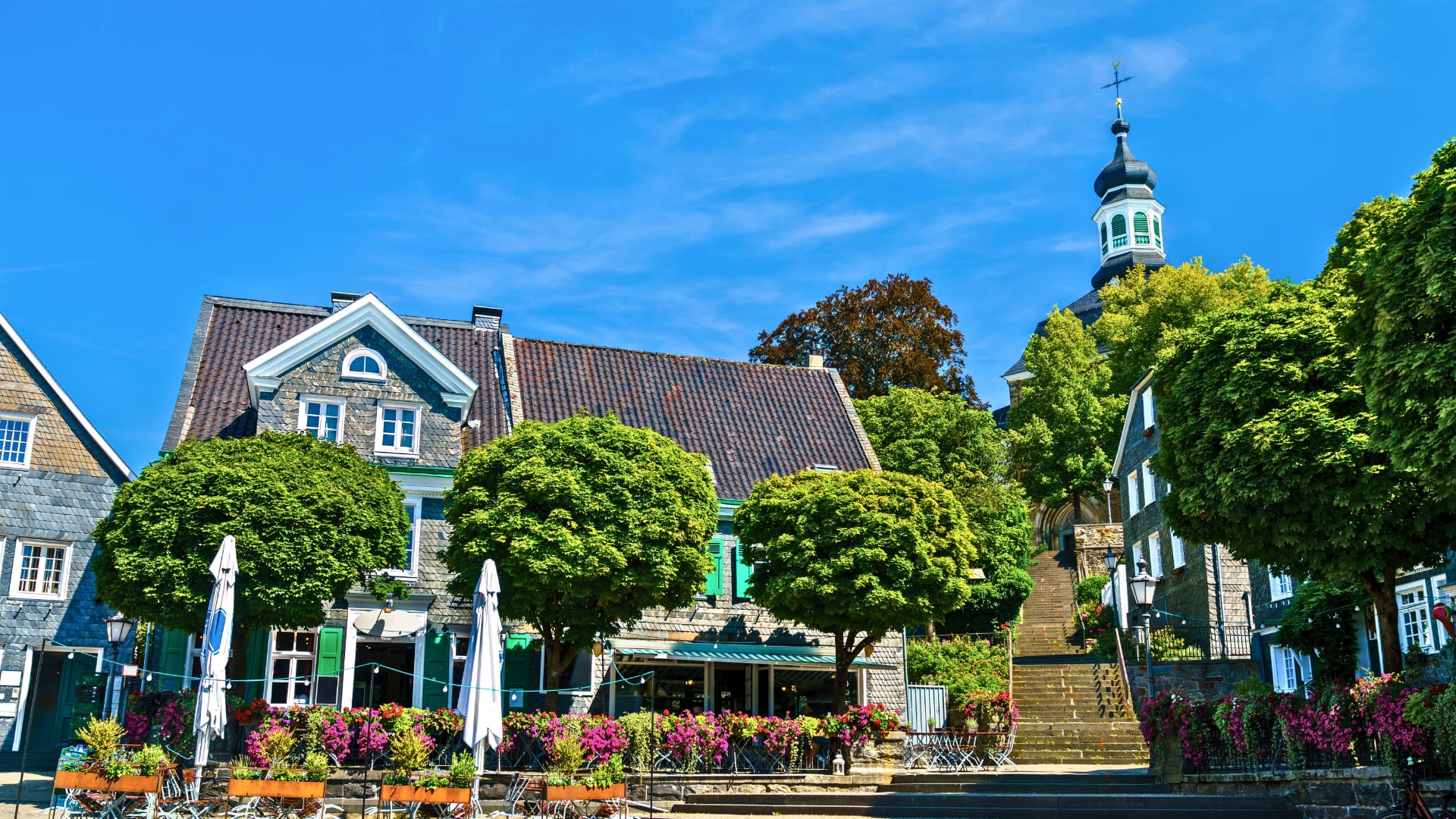 Blick auf ein historisches Gebäude mit grünen Bäumen und einer Kirche im Hintergrund in Solingen.