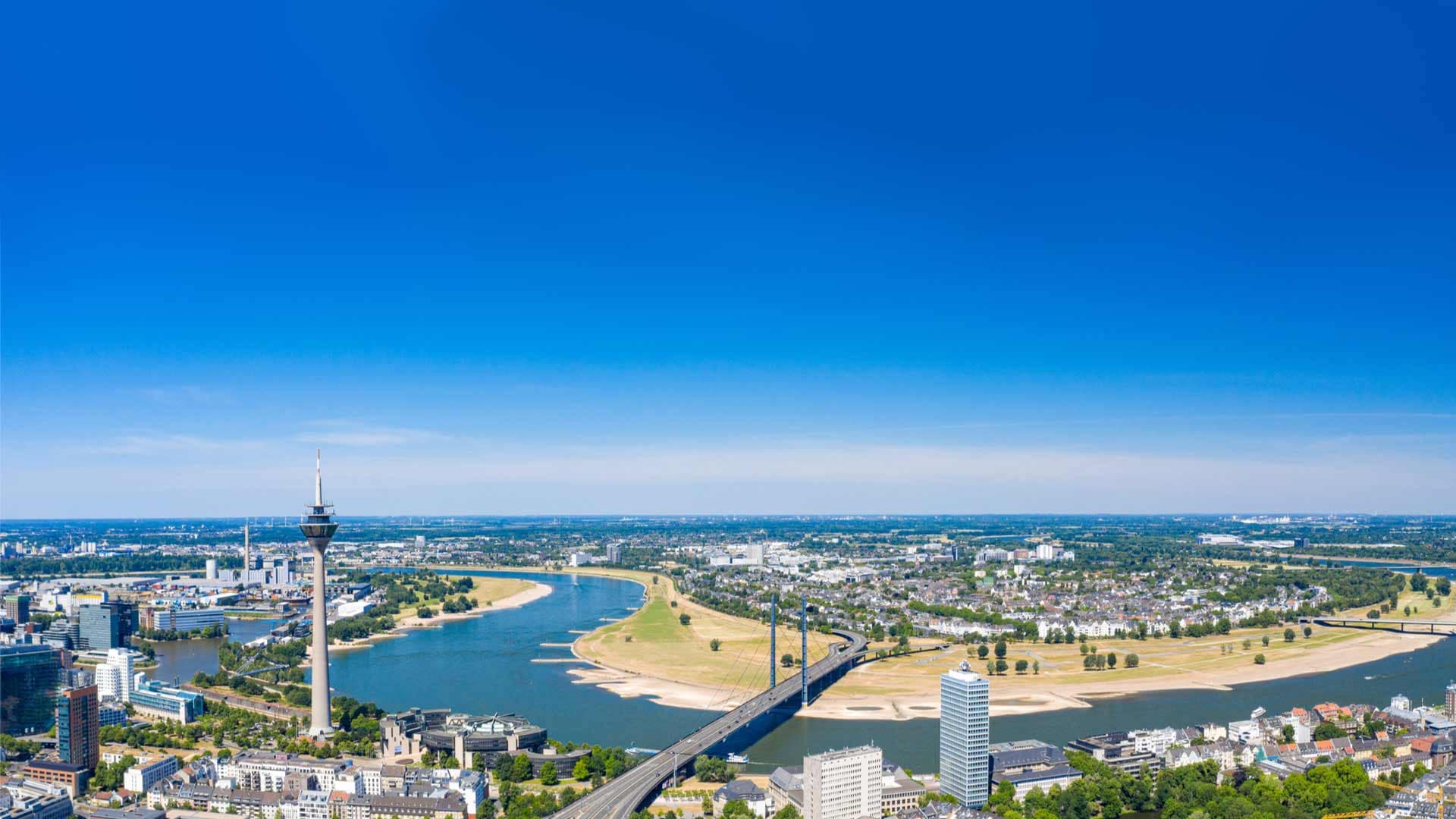 Luftaufnahme des Rheins in Düsseldorf mit dem Fernsehturm und der Oberkasseler Brücke im Vordergrund.