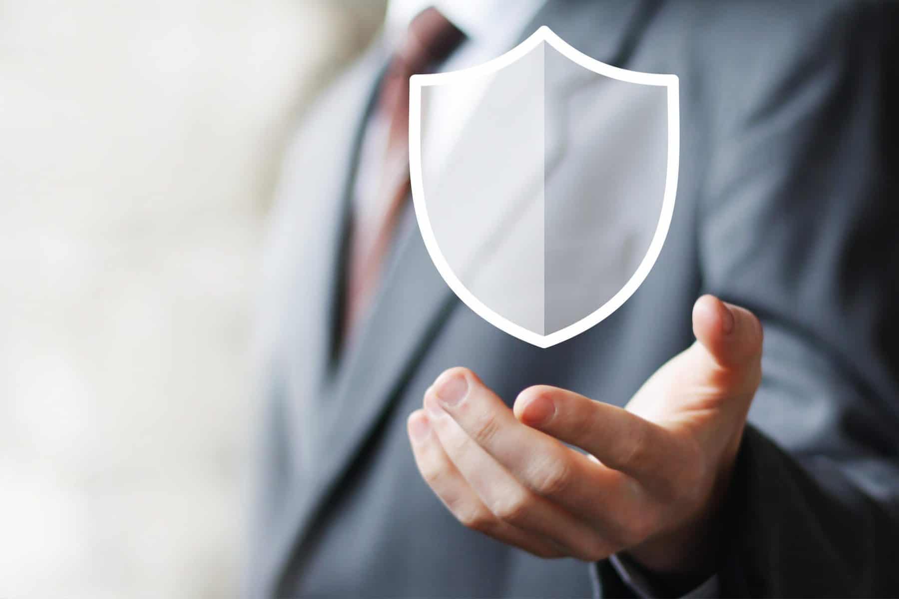 Mann in einem Anzug, der eine Hand mit einem transparenten Schutzschild-Symbol ausstreckt.
