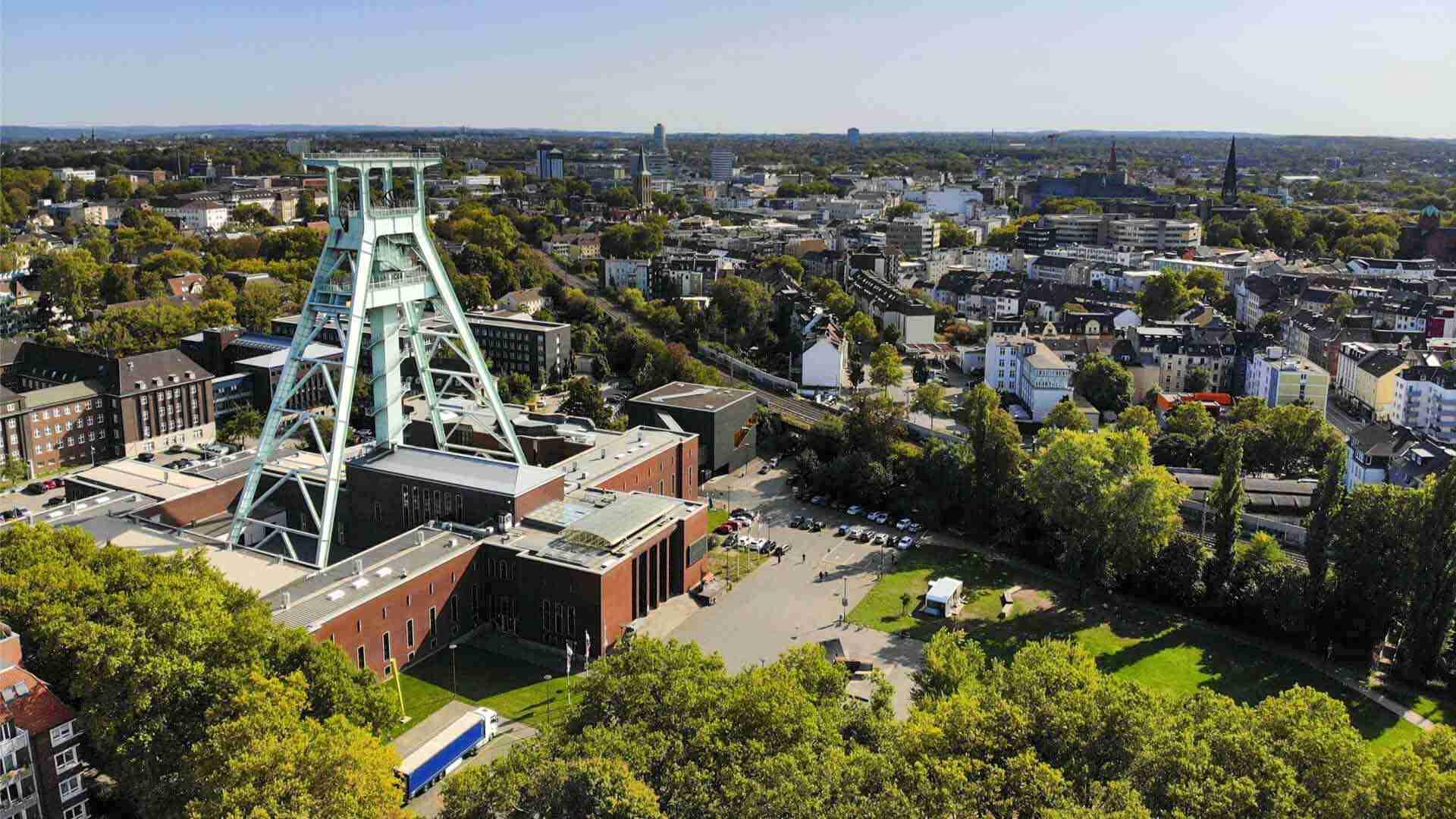 Luftaufnahme des Förderturms in Bochum mit umliegenden Gebäuden und Bäumen.