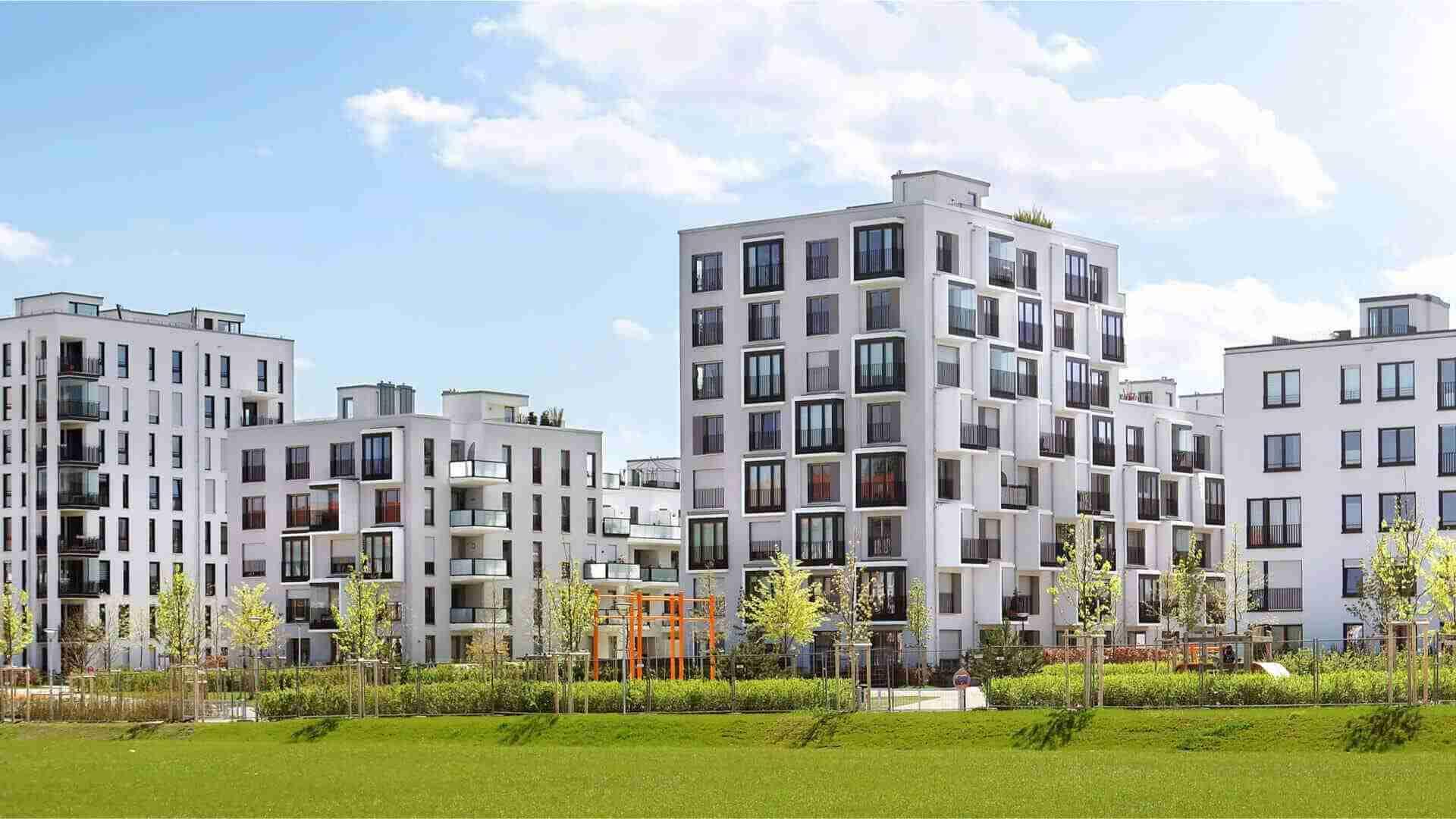 Moderne Wohngebäude mit mehreren Etagen, großen Fenstern und Balkonen in einem urbanen Umfeld.